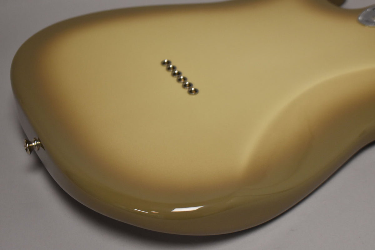 The guitar's Antigua finish is shown from the back, with six chrome string-through-body ferrules and a strap button visible.