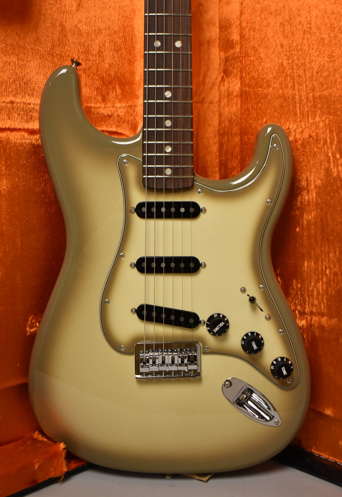 The Antigua Stratocaster's body and pickguard are a light cream, fading to a darker olive green at the edges, with a rosewood fretboard.