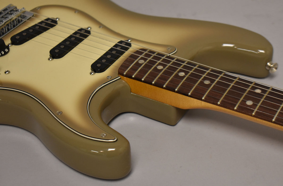 The Antigua Stratocaster's body and pickguard show a cream-to-olive sunburst, with three black single-coil pickups and a rosewood fretboard.