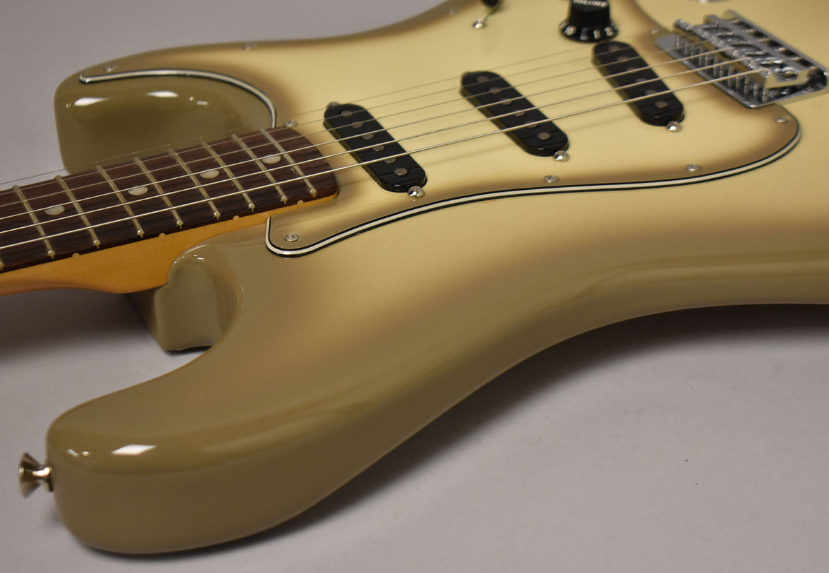 The Antigua Stratocaster's lower body and neck are angled from the left, showing its cream-to-brown burst finish and three black single-coil pickups.