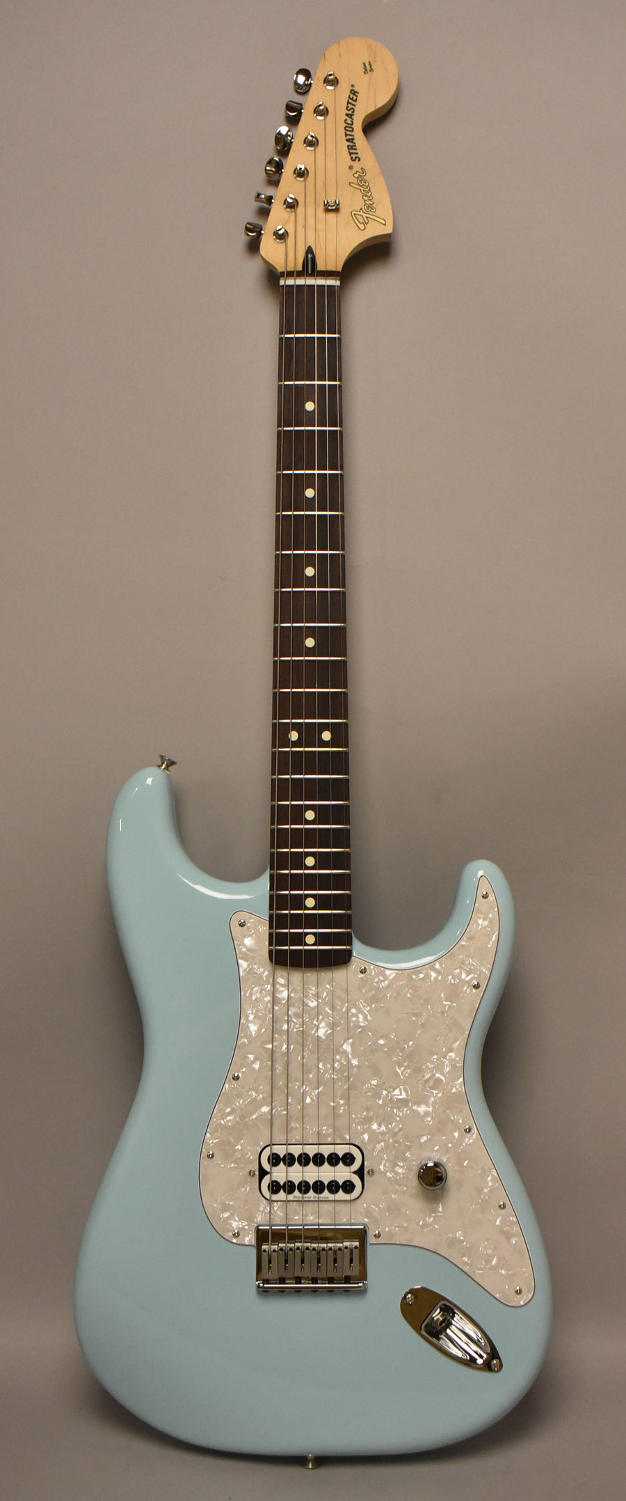 Full-length view of a Daphne Blue Stratocaster with a pearloid pickguard, single humbucker pickup, and one chrome control knob.