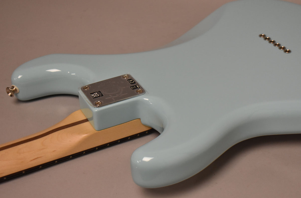 The guitar's Daphne Blue body, with a glossy finish, shows the neck joint plate and six string-through-body ferrules on the back.