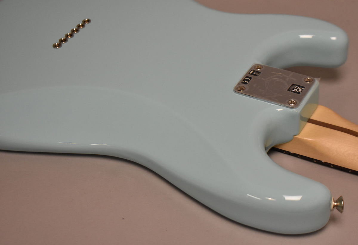 The guitar's Daphne Blue body, with a glossy finish, shows the neck plate, strap button, and six string-through-body ferrules.