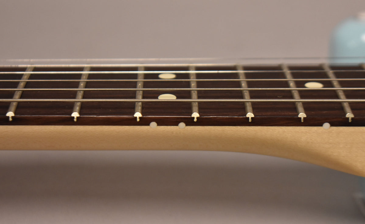 Close-up of the dark fretboard and light maple neck, showing white dot inlays on the fretboard and side.