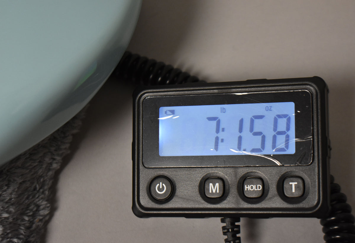 Close-up of a digital scale displaying "7 lb 15.8 oz", with the Daphne Blue guitar body partially visible on the left.