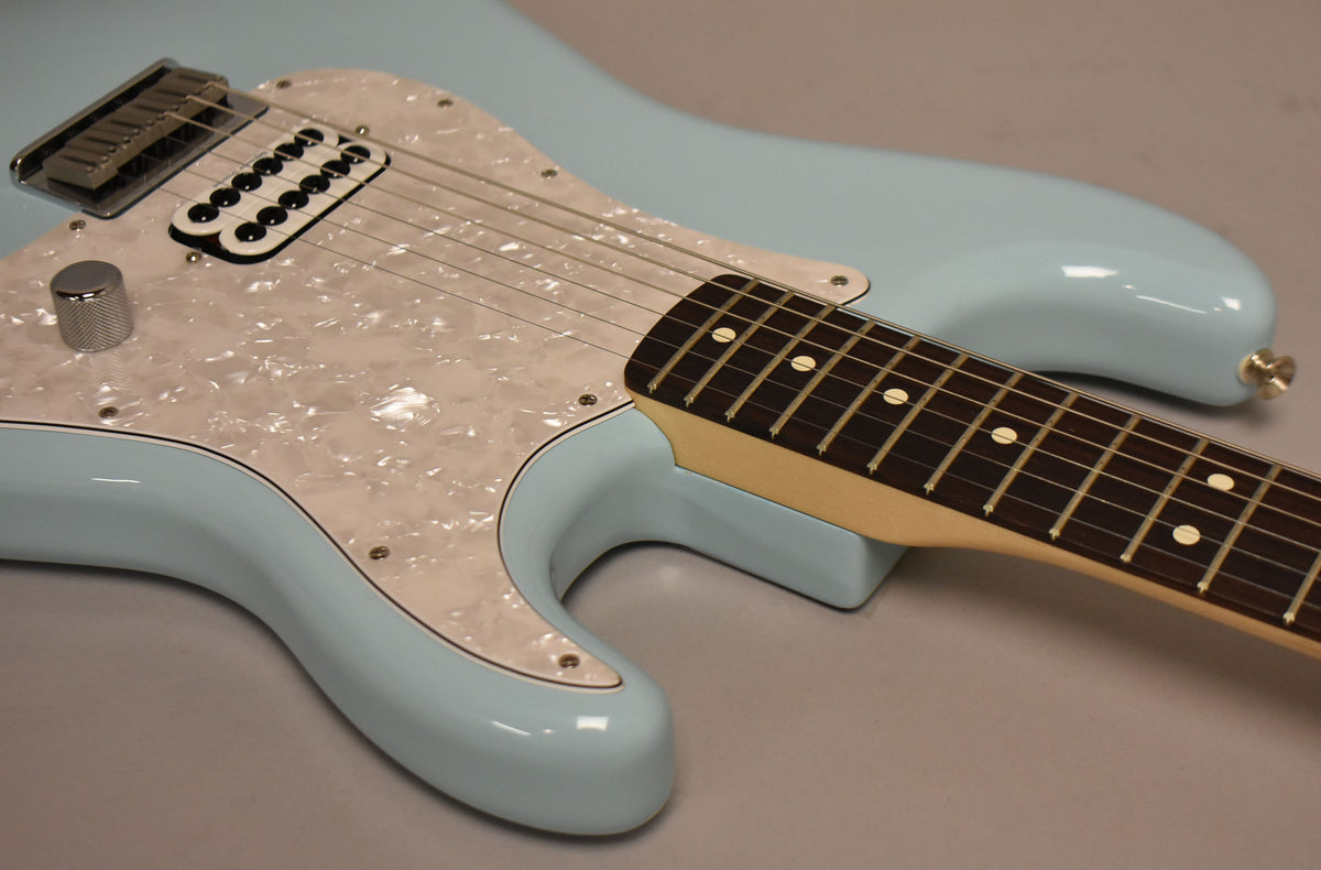 A Daphne Blue Stratocaster, angled from the lower bout, features a pearloid pickguard, single humbucker, and a chrome volume knob.