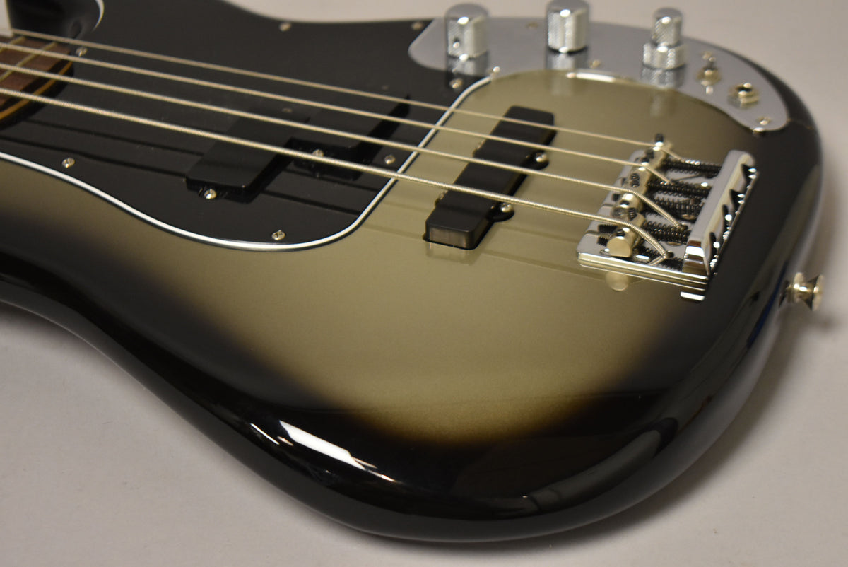 The bass body, angled from above, shows a glossy silverburst finish, black pickguard, two pickups, and chrome hardware.