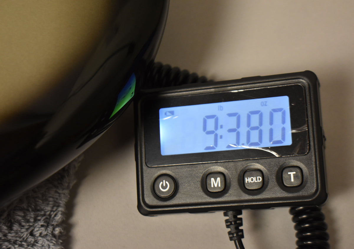 The bass body's dark silverburst finish is visible next to a digital scale displaying "9.380 lb" in blue.