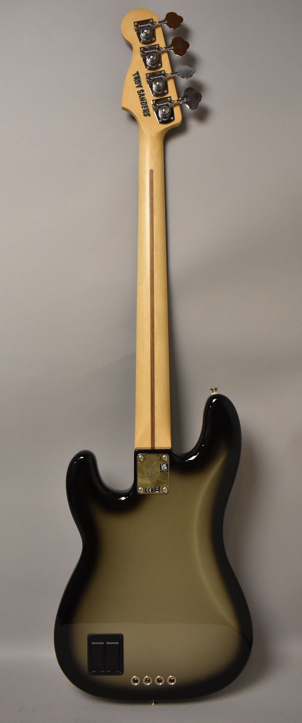 Rear view of a Silverburst bass, showing the headstock with four tuners, a maple neck with a dark stripe, and a glossy body.