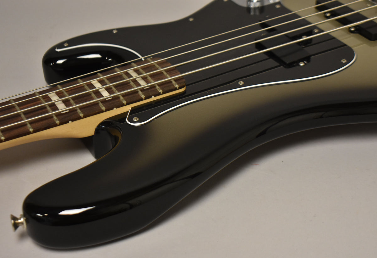 The bass body, in a glossy silverburst finish, shows a black pickguard, split pickup, and a rosewood fretboard with block inlays.