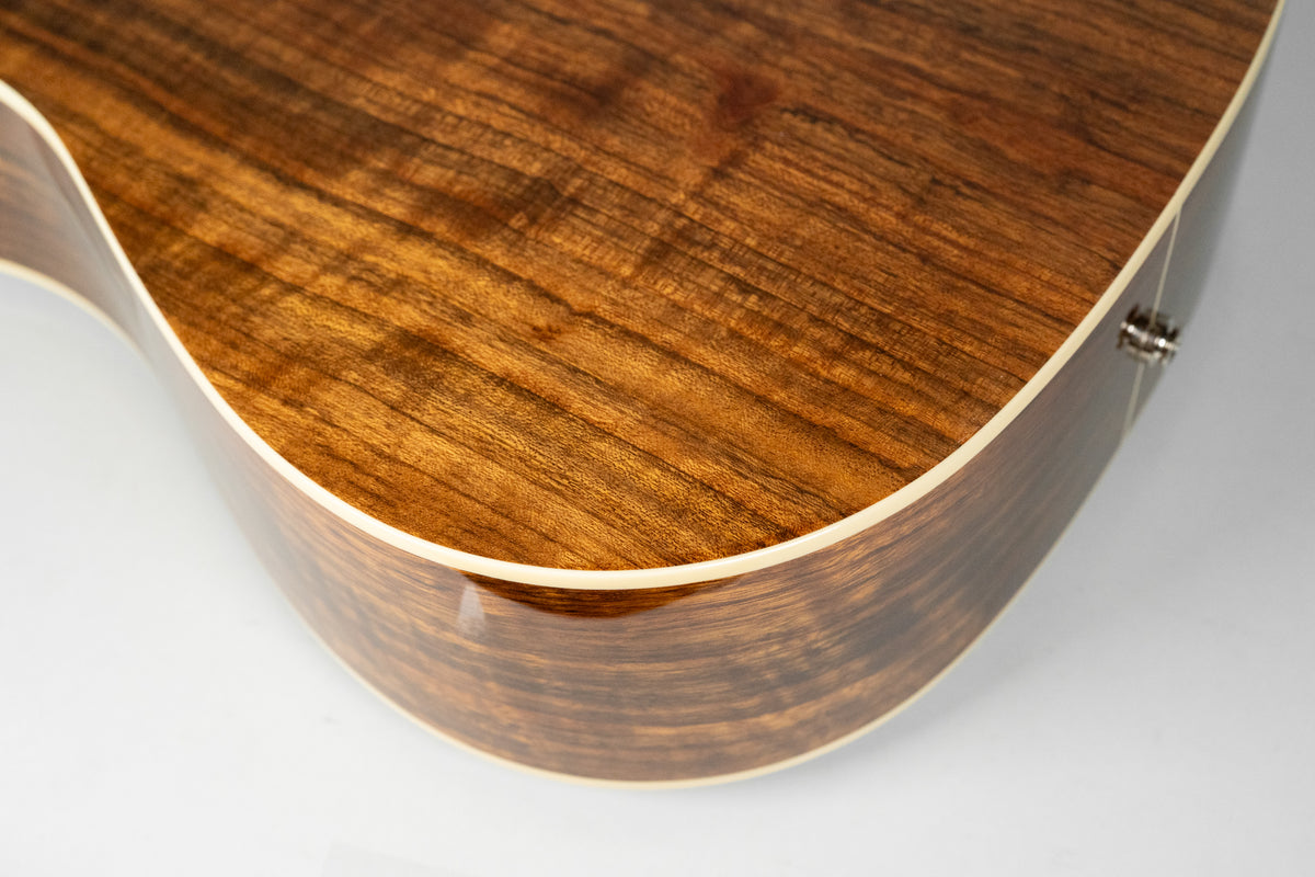 Close-up of the guitar's lower bout, showing the glossy, dark brown wood grain of the back and side, with cream binding.