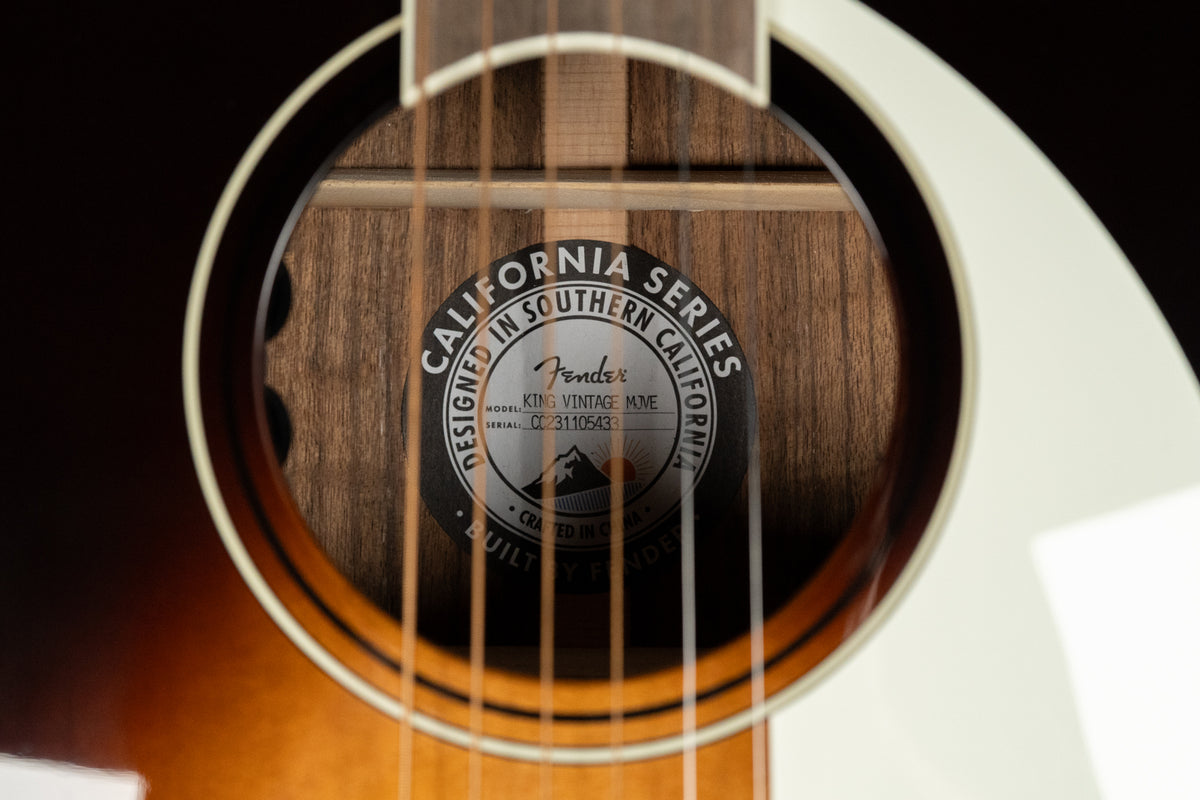 Close-up of the sunburst acoustic guitar's soundhole, revealing the internal label and dark wood grain inside.