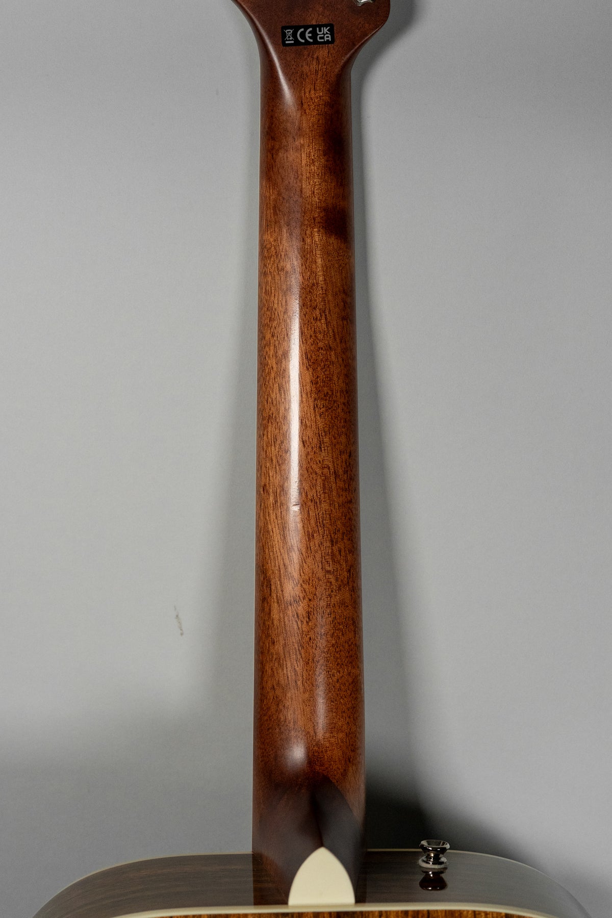 The back of the guitar's mahogany neck and heel are visible, with a small ding on the neck and a strap button on the body.