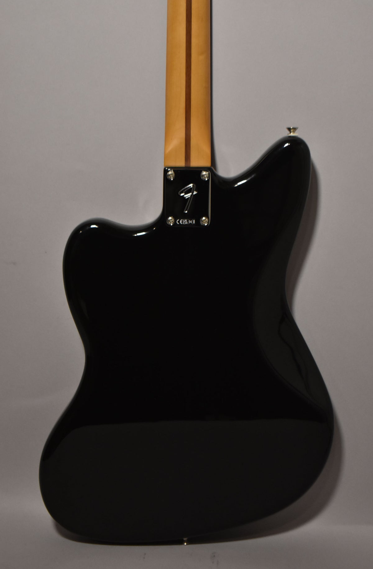 Rear view of the black gloss Jazzmaster body, showing the chrome neck plate with a Fender logo and the light wood neck.