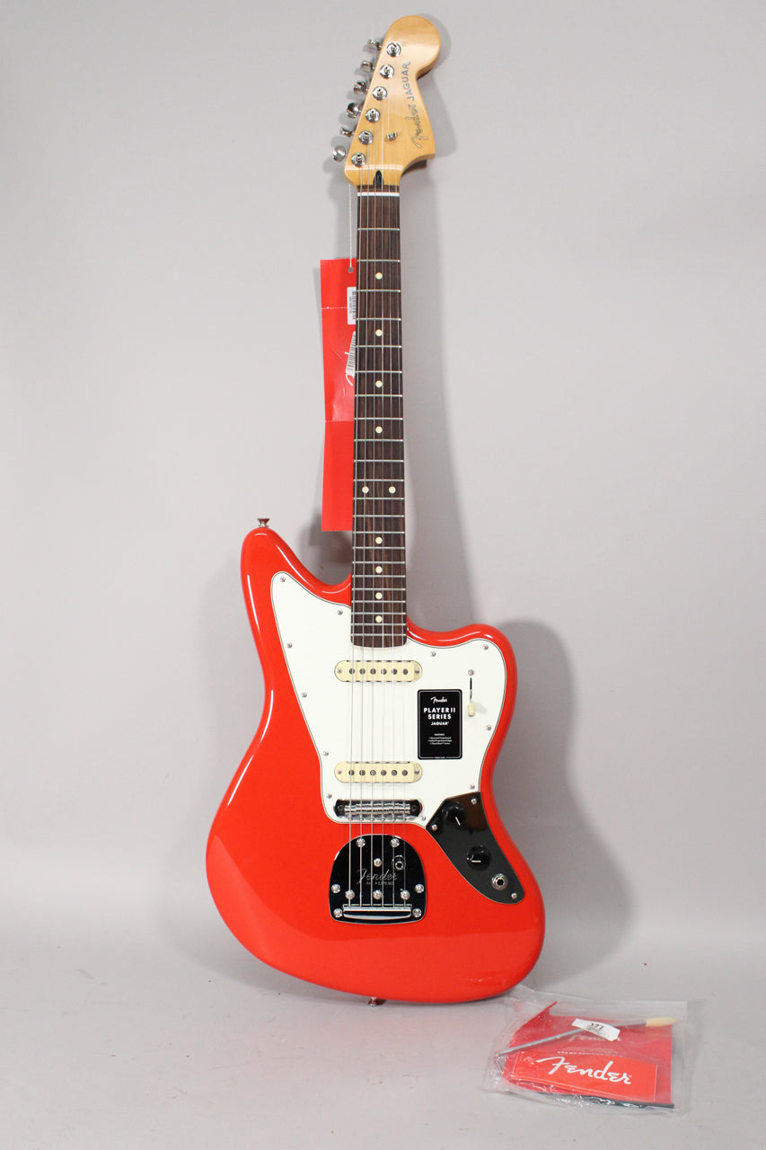 Full-length view of a glossy coral red Jaguar electric guitar with a white pickguard, chrome hardware, and two single-coil pickups.