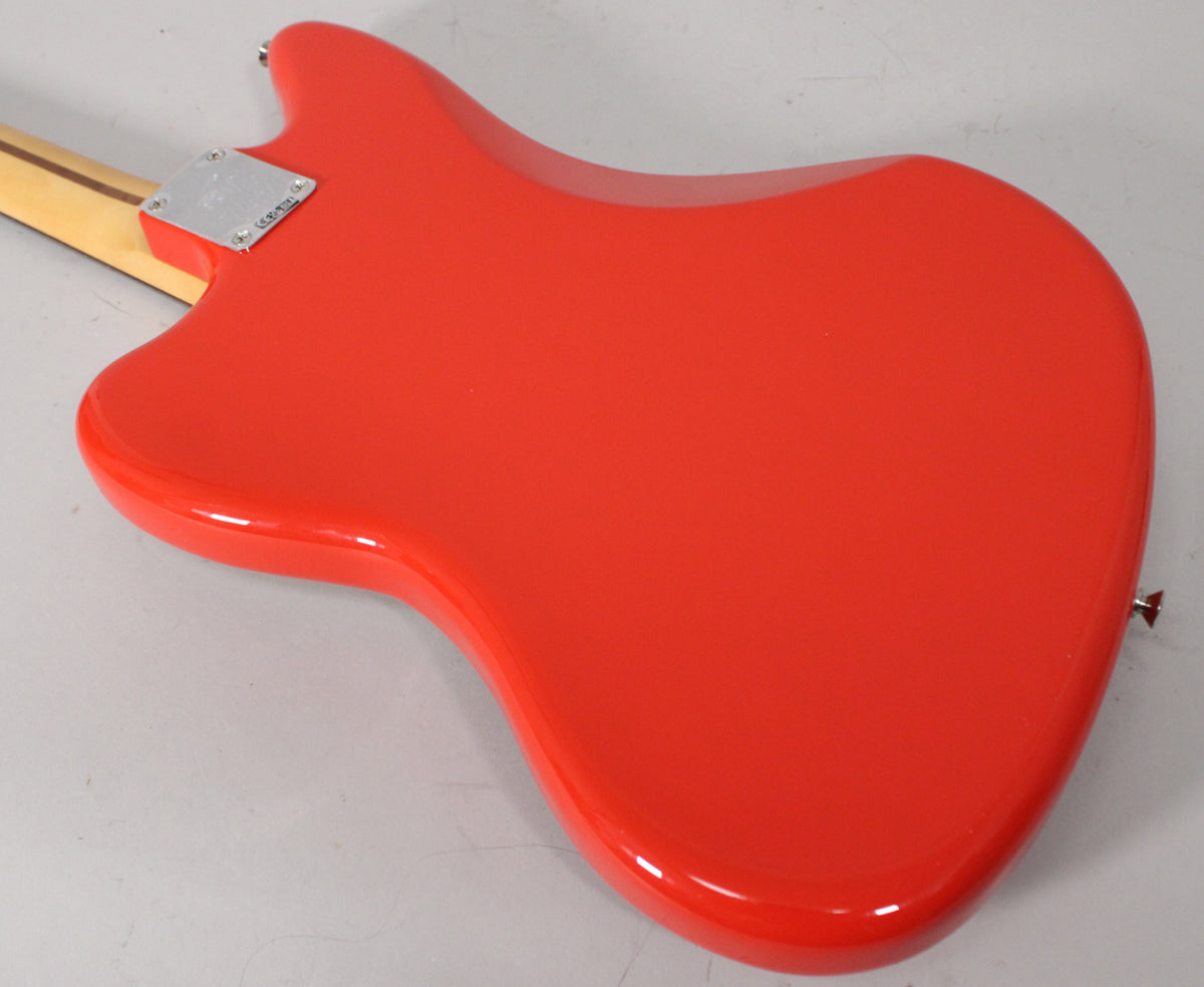 The glossy coral red Jaguar body is angled, showing the back with a chrome neck plate and a strap button on the lower bout.