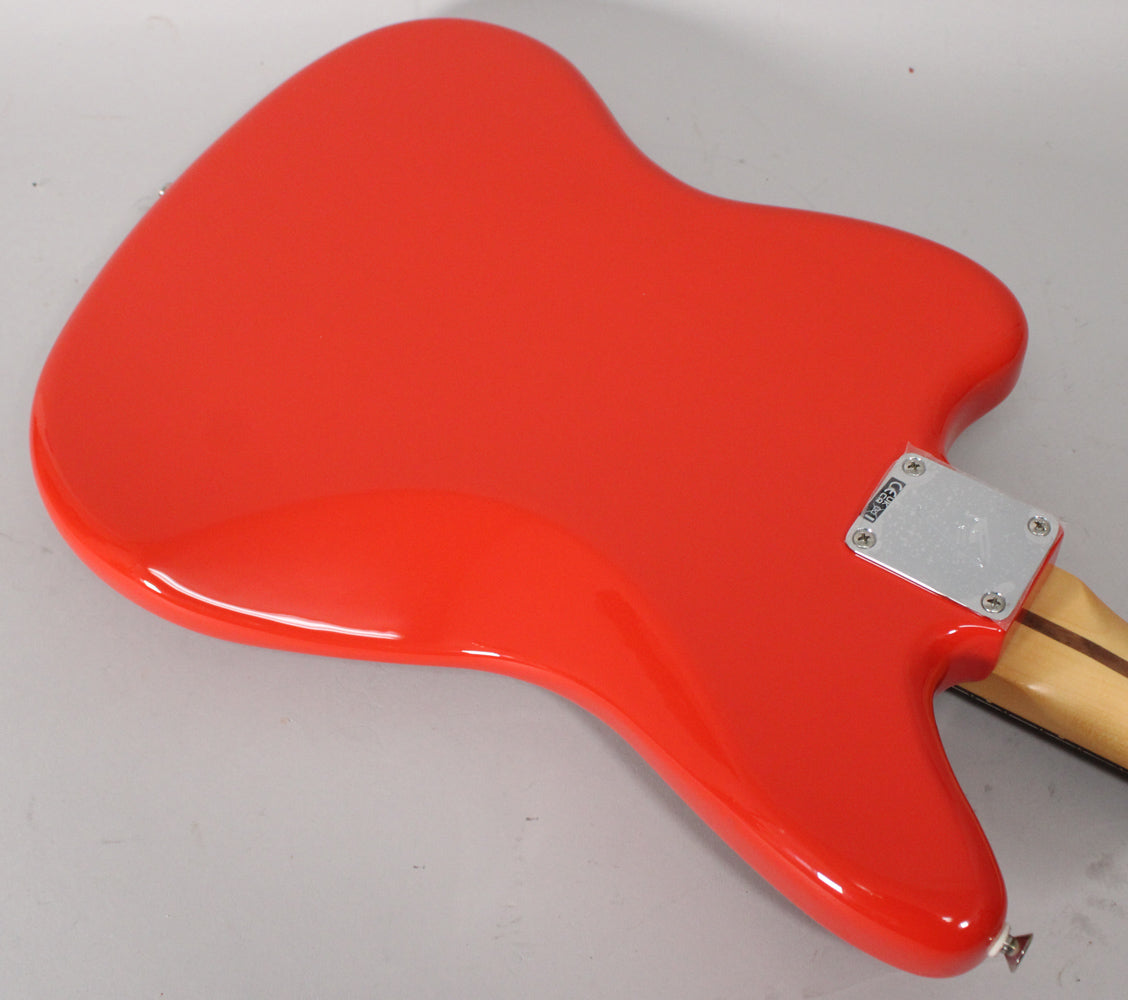 The back of a glossy coral red Jaguar guitar body, with a chrome neck plate and a light wood neck.