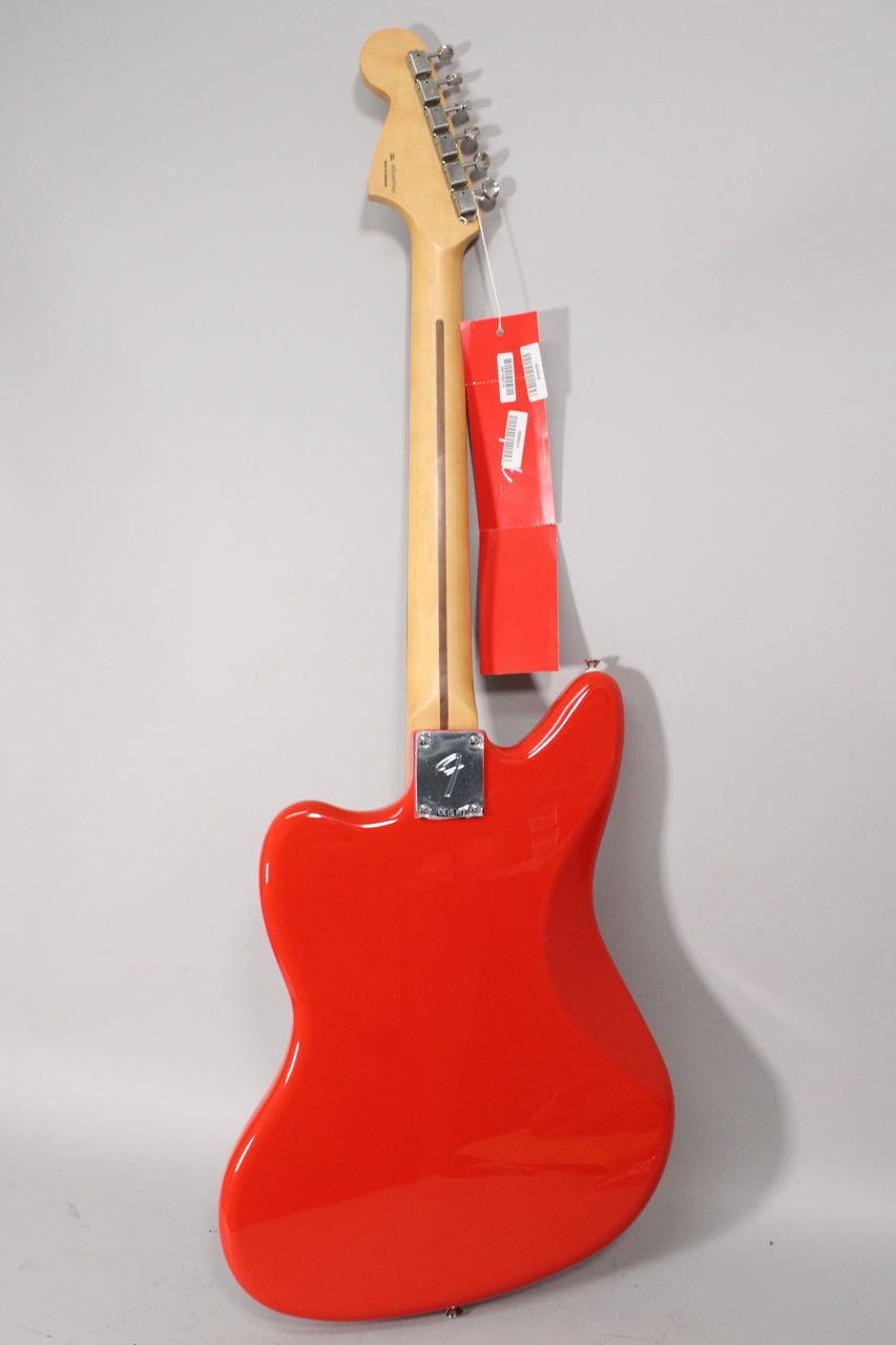 The back of a glossy coral red Jaguar electric guitar, angled slightly right, with a light maple neck and chrome tuners.