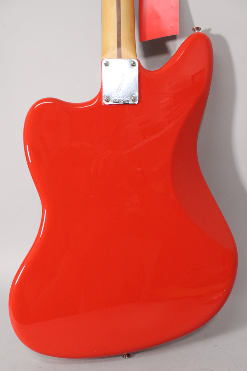 The back of the glossy coral red Jaguar body is shown, with a chrome neck plate and a light wood neck extending upwards.