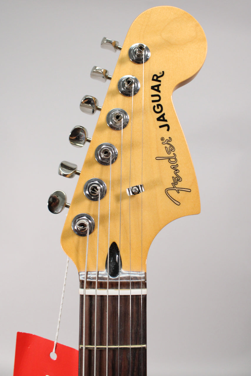 Close-up of the guitar's headstock, showing six chrome tuners, a string tree, and a dark rosewood fretboard with frets.