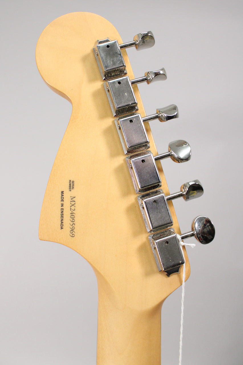 The back of a light maple headstock and neck, with six chrome tuning machines and a white string tag.