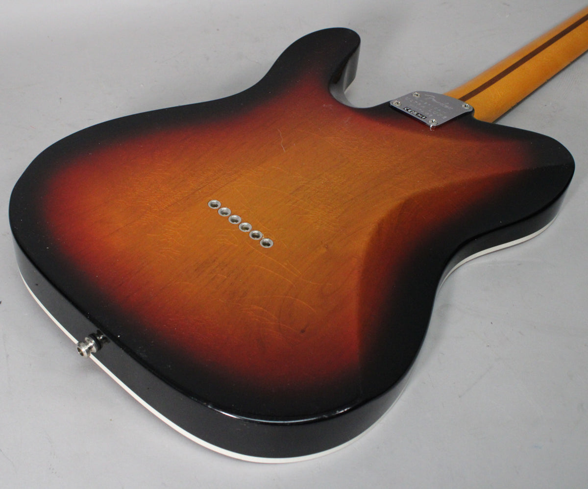The guitar's 3-color sunburst back shows light wear, with six string-through-body ferrules and a chrome neck plate.
