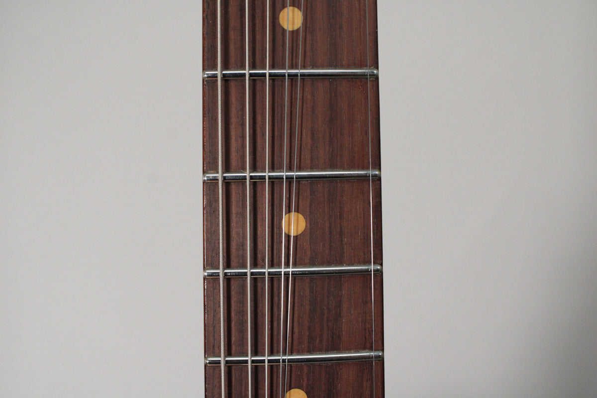 Close-up of the dark rosewood fretboard with light-colored dot inlays and silver frets, angled slightly to the left.