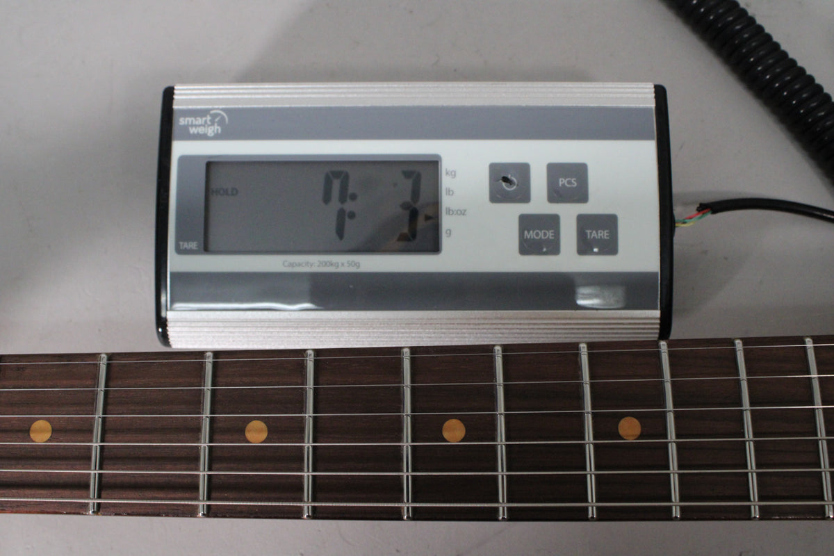 The guitar's dark rosewood fretboard with round yellow inlays is visible below a digital scale displaying "7.3".