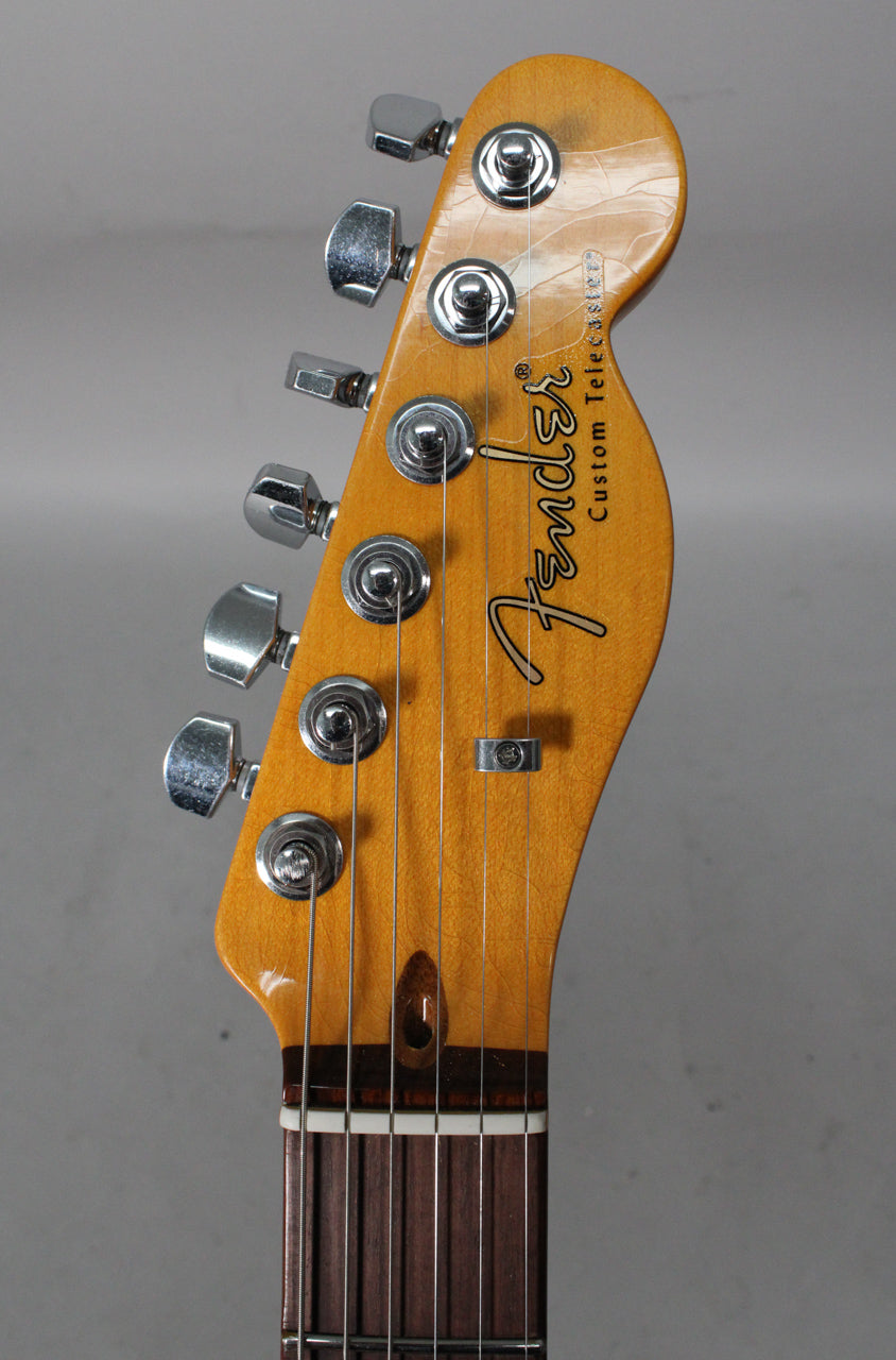 Close-up of the guitar's headstock, showing six chrome tuning pegs, a string tree, and a vintage-style finish with visible checking.