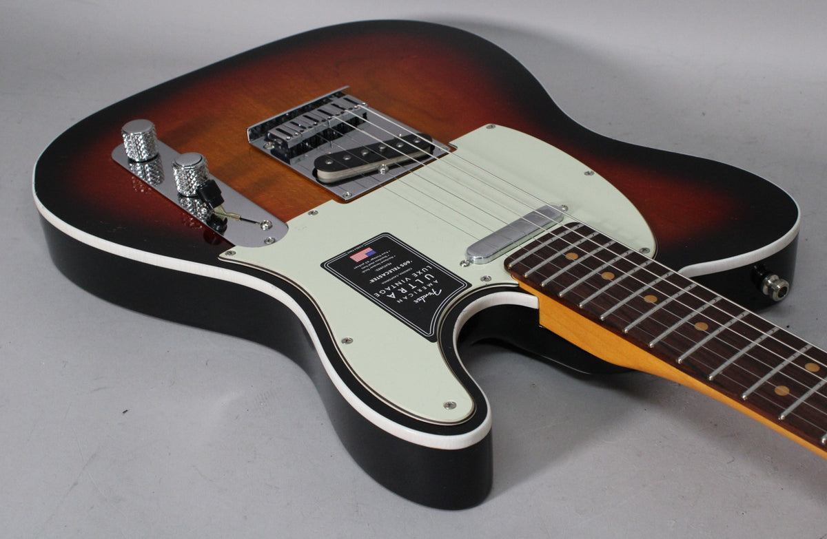 A 3-color sunburst Telecaster, angled from the lower bout, showing its cream pickguard, chrome hardware, and dark rosewood fretboard.