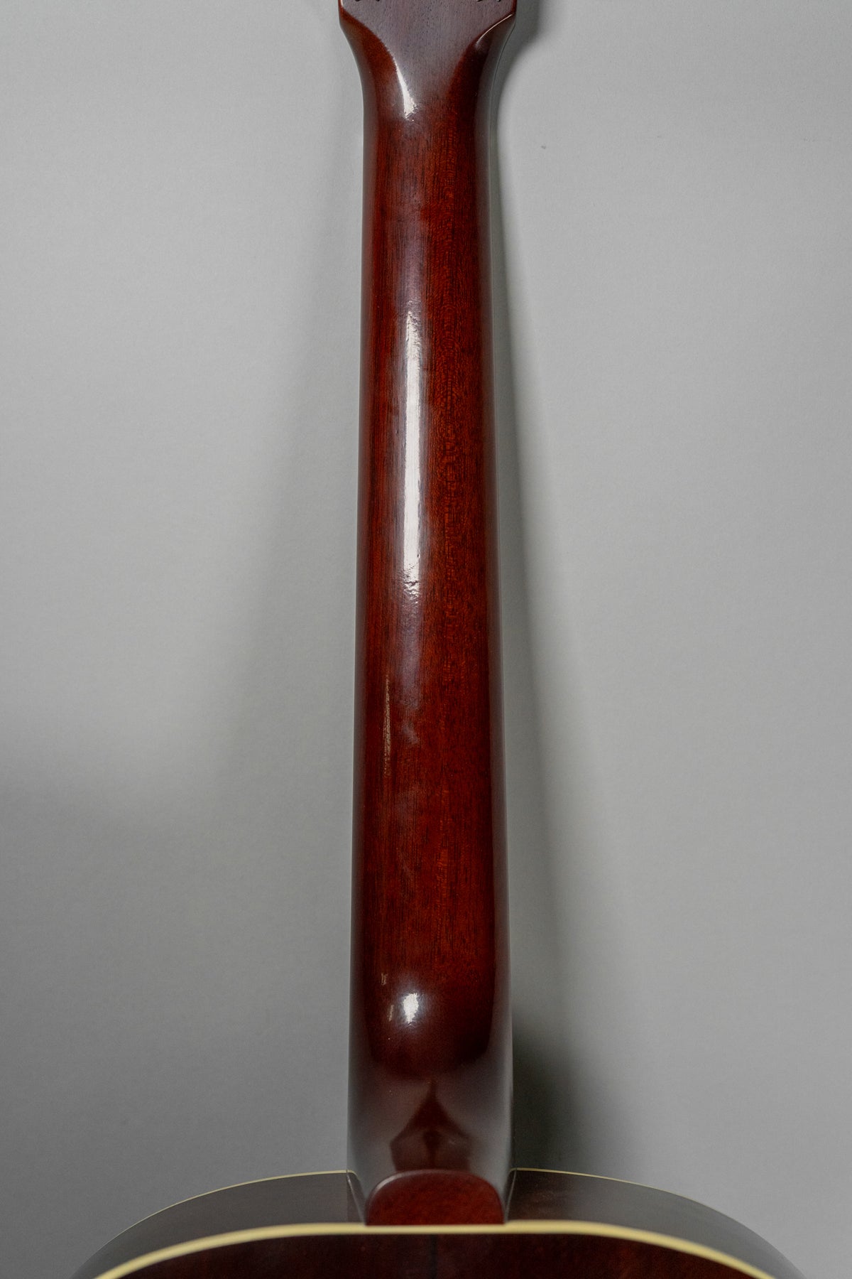 The guitar's dark reddish-brown neck and heel are visible from the back, with a glossy finish and light wear.