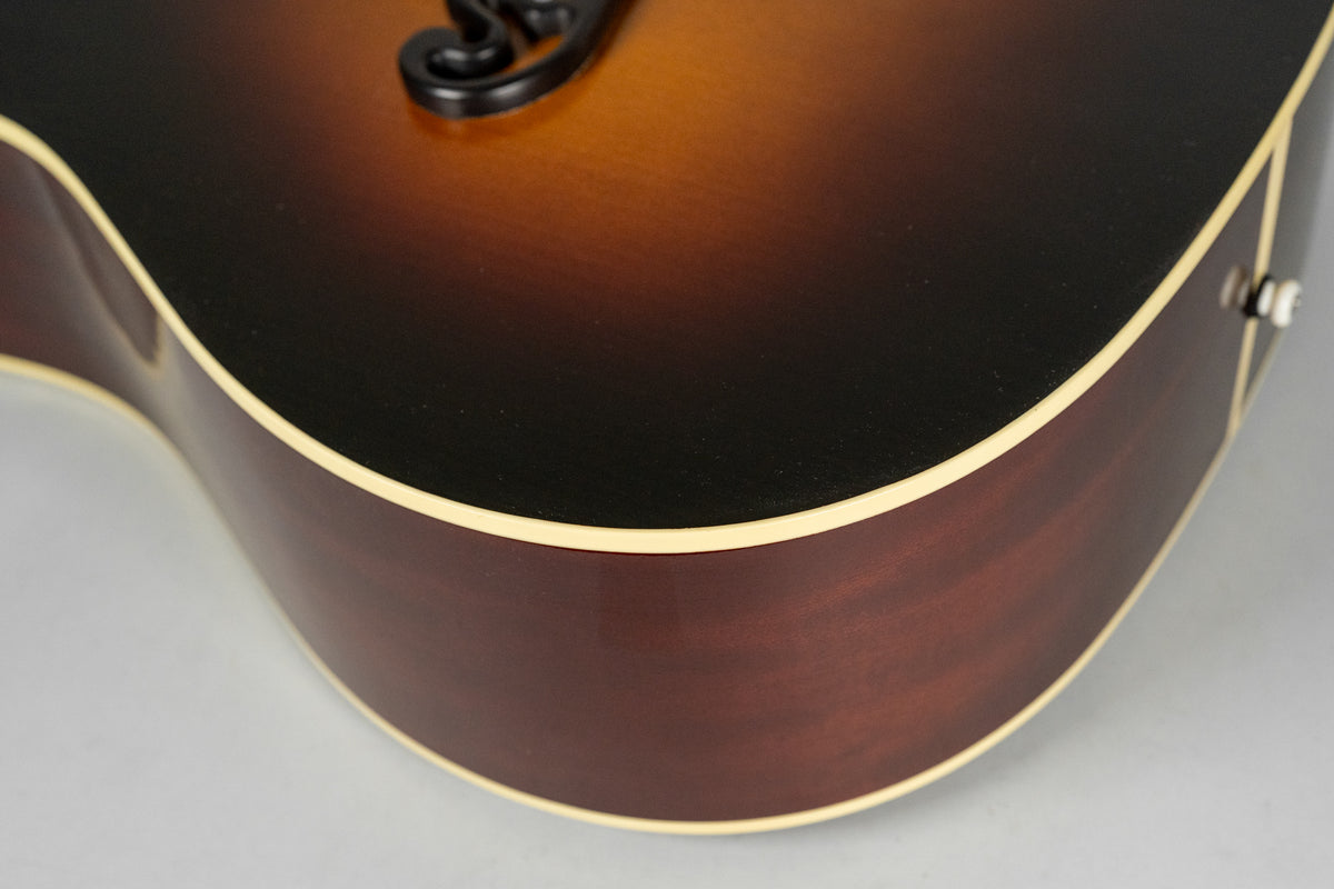 Close-up of the guitar's lower bout, showing the dark brown sunburst top, dark reddish-brown sides, and cream binding.