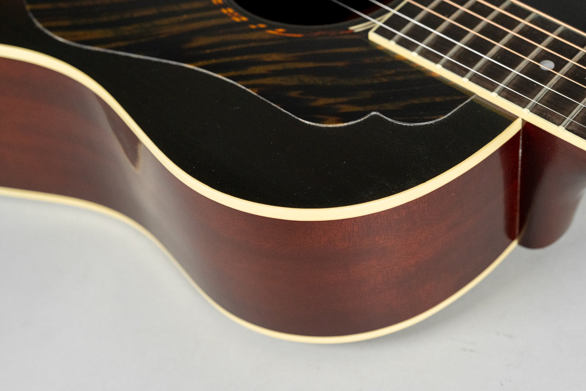 Close-up of the guitar's lower bout, showing the dark brown sides, cream binding, and a black pickguard with a tiger-stripe pattern.