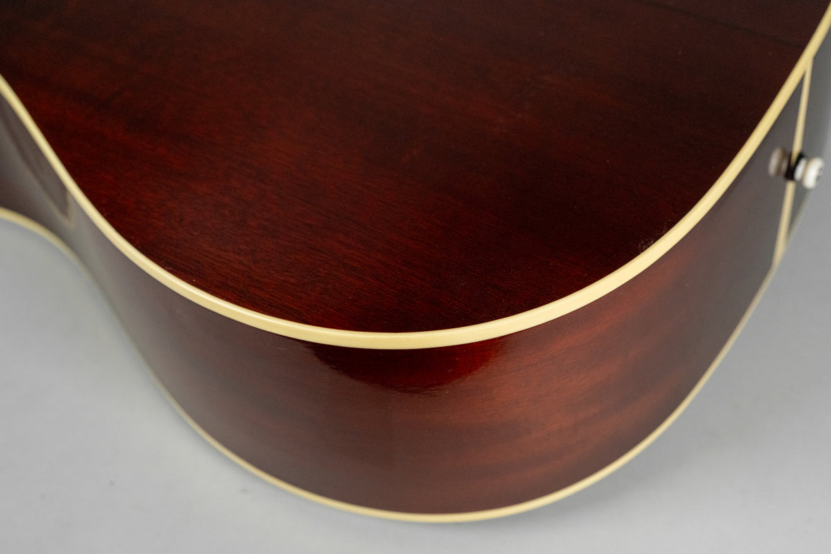 Close-up of the lower bout of the dark reddish-brown acoustic guitar, showing the body's curve and cream binding.
