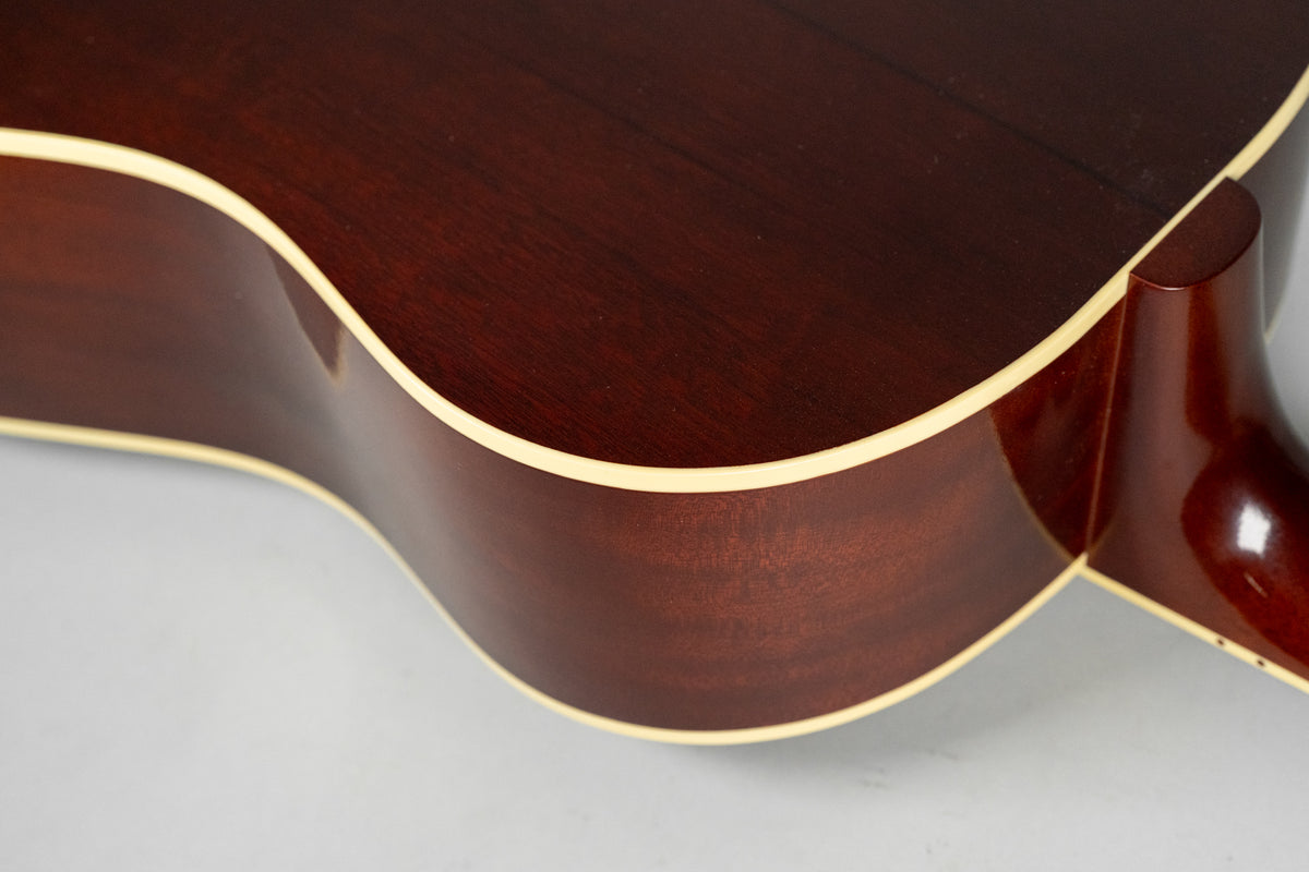 Close-up of the guitar's dark reddish-brown body and neck heel, showing the cream binding along the curved edge.