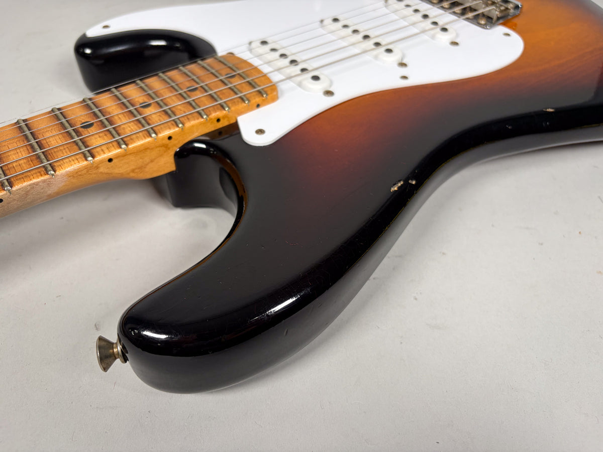 Close-up of the guitar's lower bout, showing the sunburst finish with visible chips and wear, a white pickguard, and a maple neck.