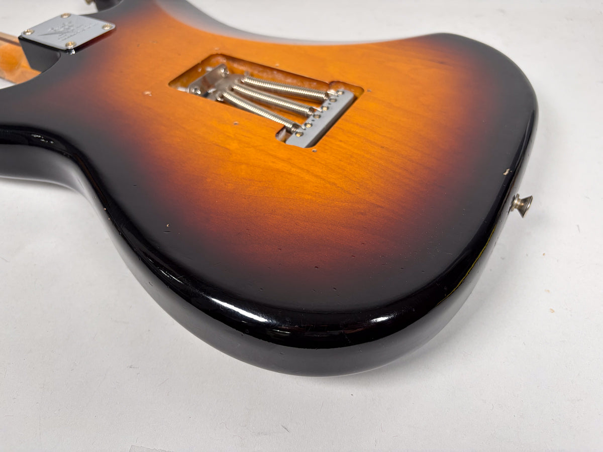 The guitar's sunburst back, with visible relic wear and checking, shows the tremolo springs and a strap button.