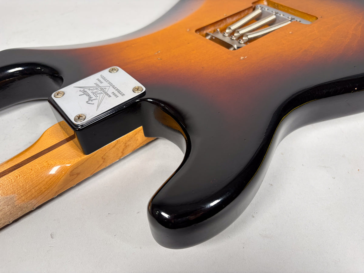 The guitar's sunburst body and maple neck meet at a chrome neck plate, with visible wear and checking on the finish.