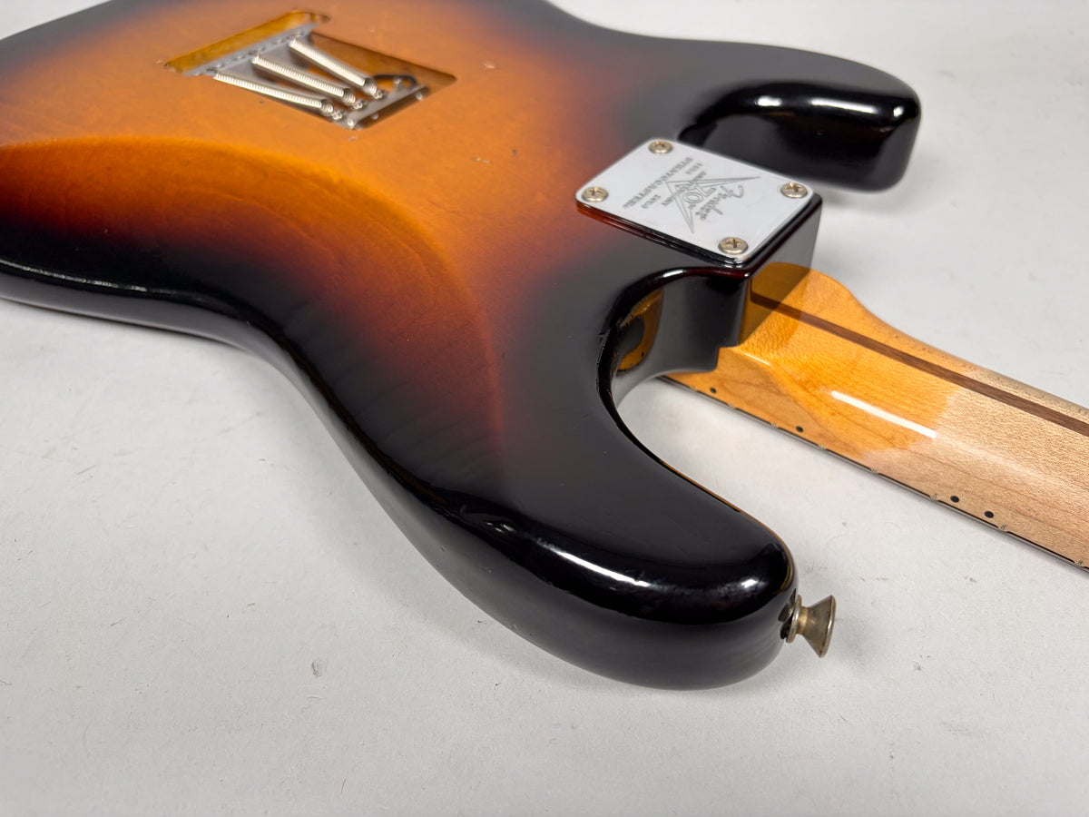 The guitar's sunburst body, showing the neck plate, neck heel, and tremolo spring cavity, has light wear and finish checking.