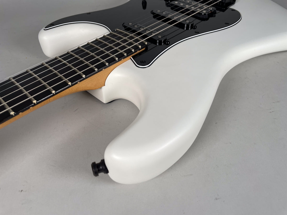 Close-up of the white Stratocaster's lower body and neck joint, showing the black pickguard, HSS pickups, and output jack.