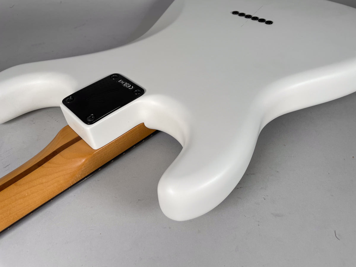 The guitar's white body, with a black neck plate and six string-through-body ferrules, meets a light wood neck.