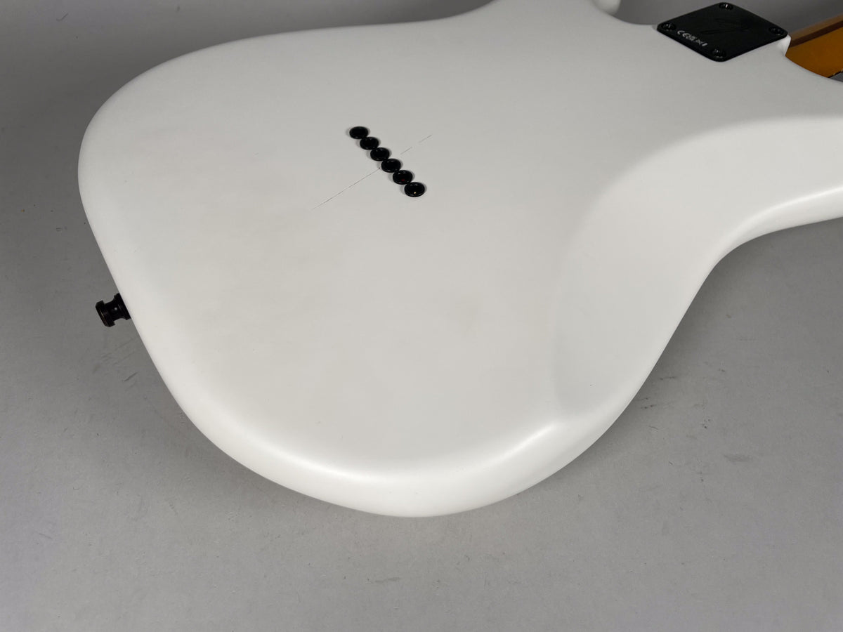 The back of a white hardtail Stratocaster body, angled from the lower bout, showing six black string ferrules and a black strap button.