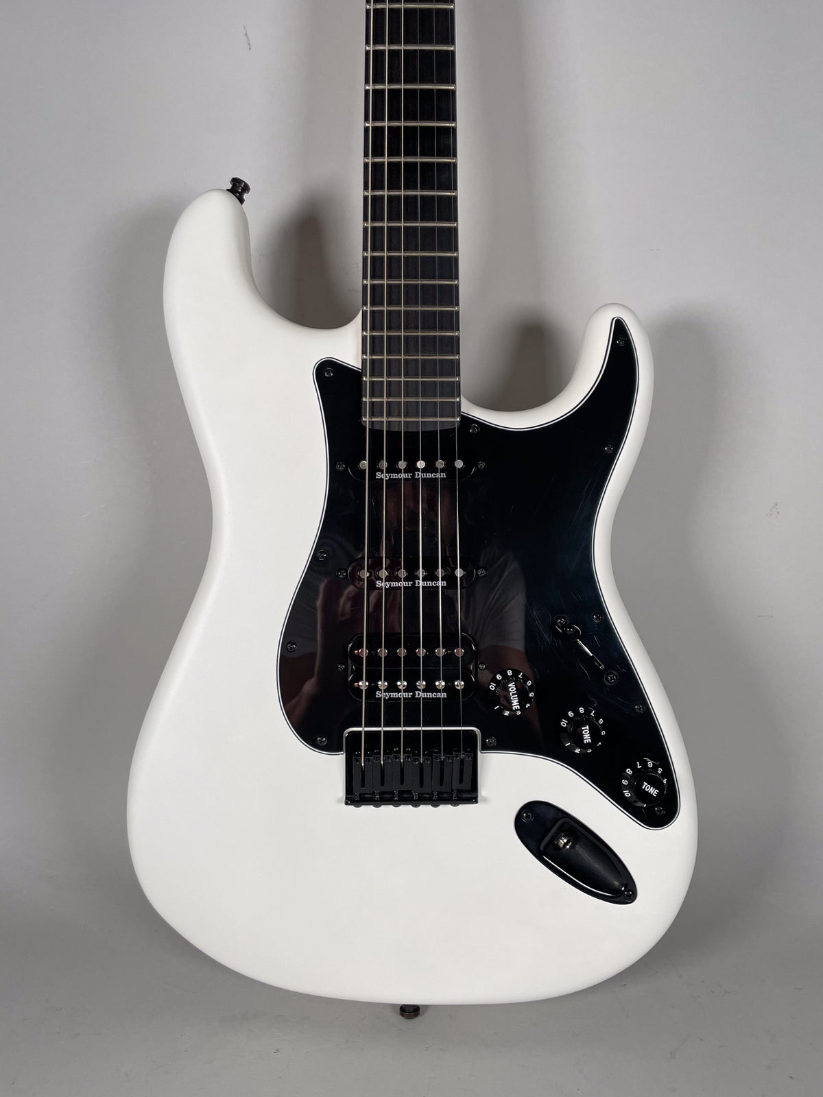 White Stratocaster body with black pickguard, HSS pickups, black hardtail bridge, and black volume/tone knobs.