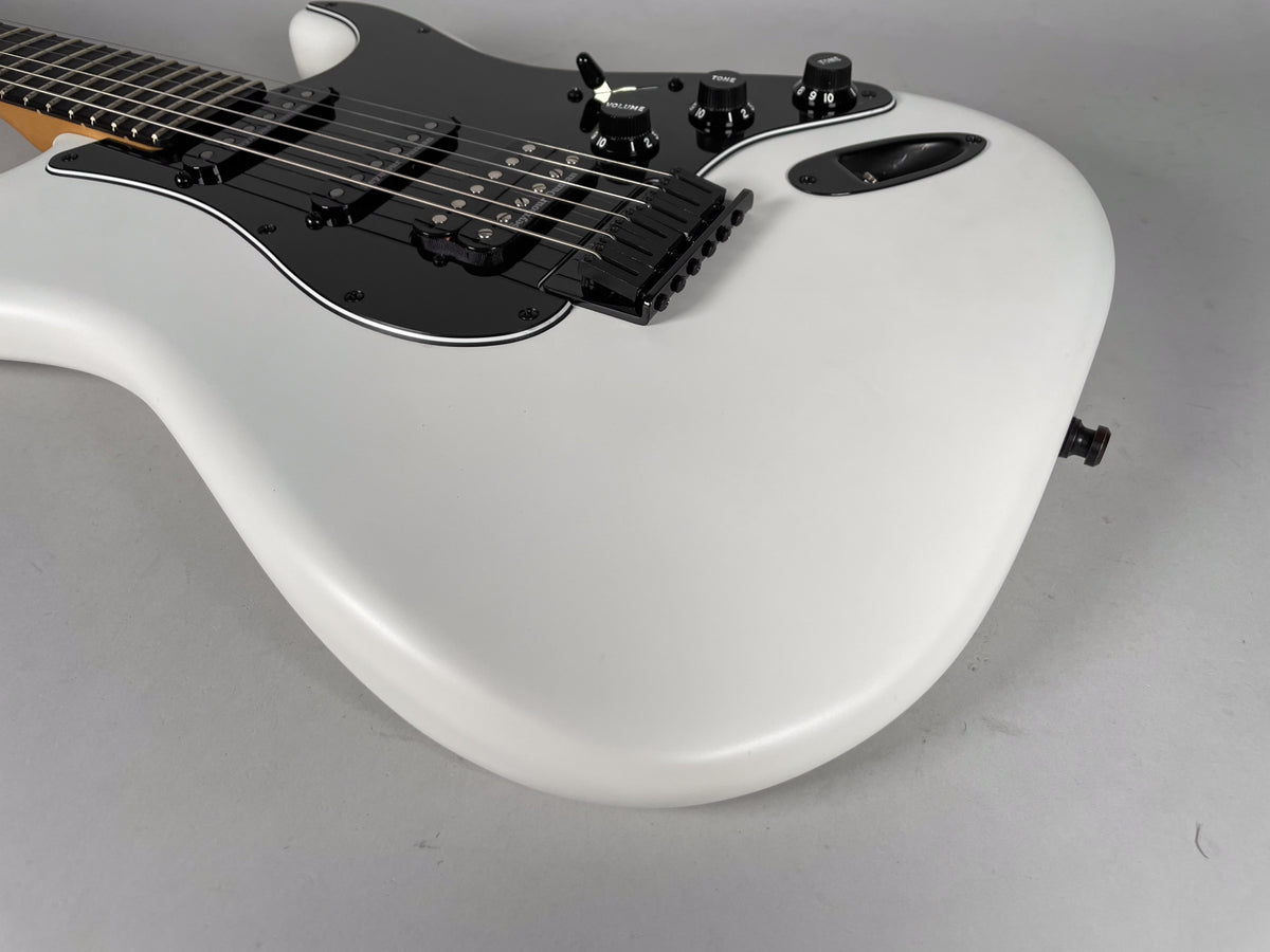 Upper body of a white Stratocaster with a black pickguard, black hardtail bridge, and black control knobs, viewed from above.