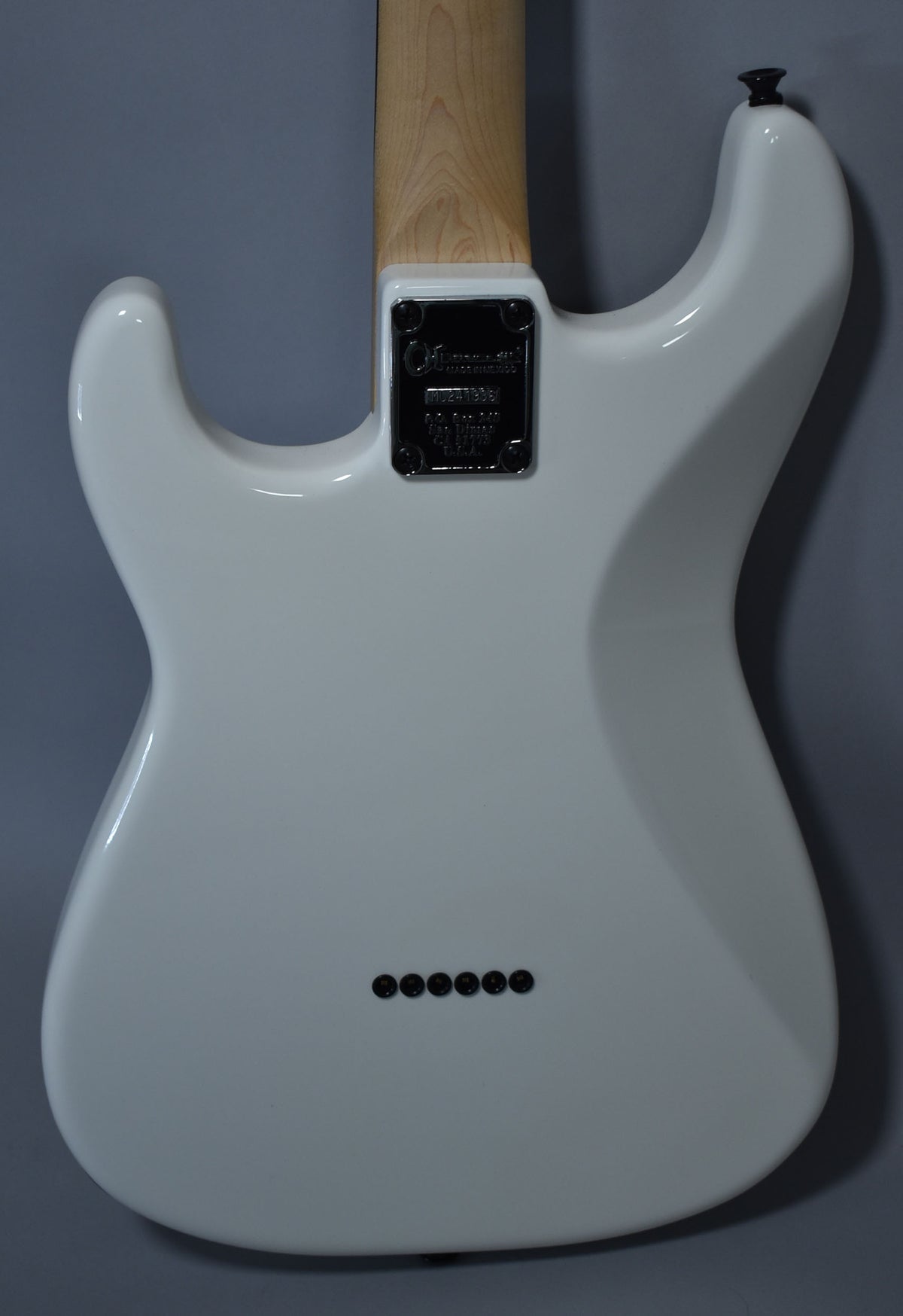 Rear view of a glossy white guitar body with a natural wood neck, black neck plate, and six black string ferrules.