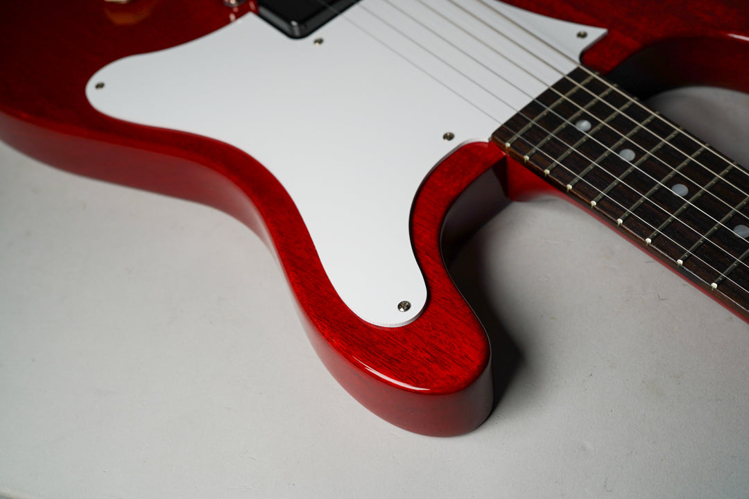 Close-up of the cherry red guitar body and white pickguard, showing the lower bout and part of the fretboard with dot inlays.
