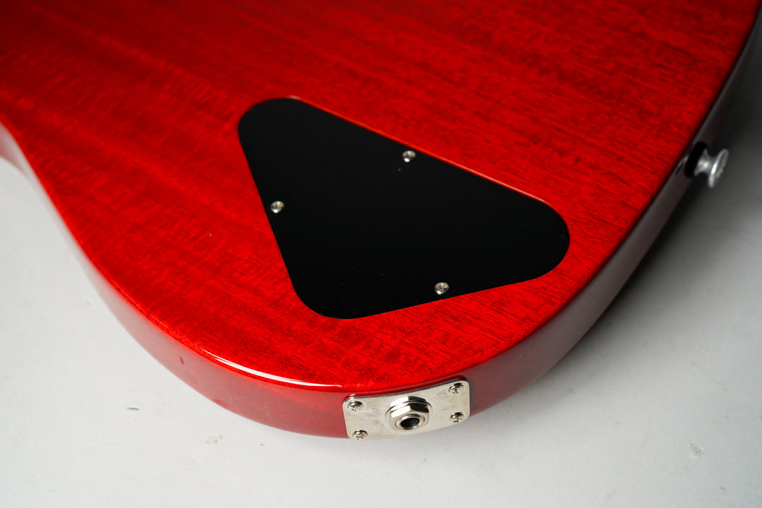 Close-up of the guitar's cherry red back, showing a black triangular control cavity cover and a chrome output jack on the lower bout.
