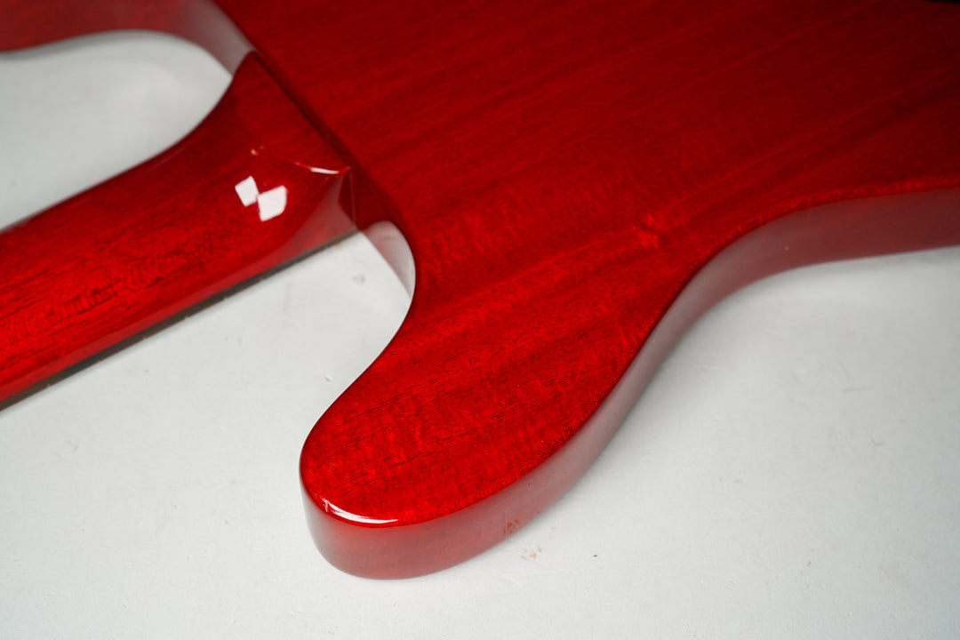 Close-up of the guitar's cherry red body and neck joint, showing the glossy finish and wood grain, with a small ding on the lower horn.