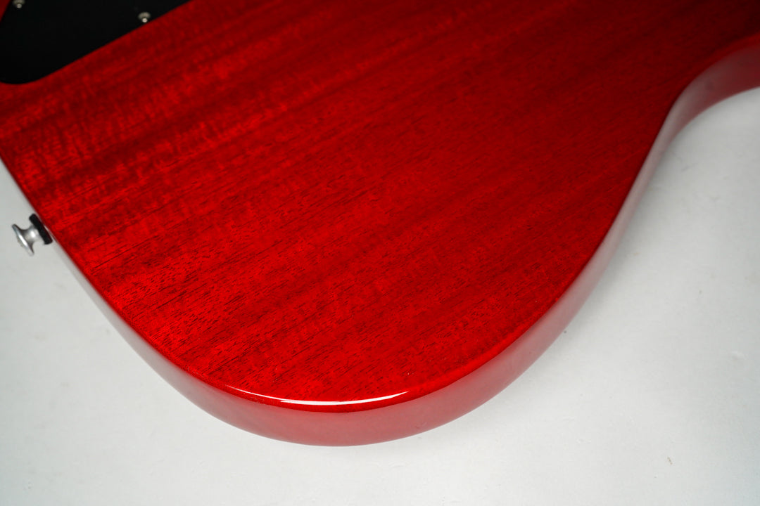 The lower bout of the cherry red guitar body, showing the glossy finish and wood grain, with a strap button visible on the left.