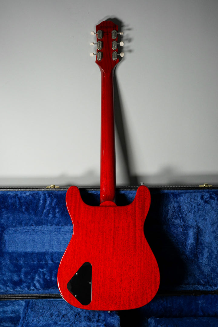 The back of a cherry red electric guitar with a glossy finish, showing the headstock, neck, and body, resting in a blue-lined case.